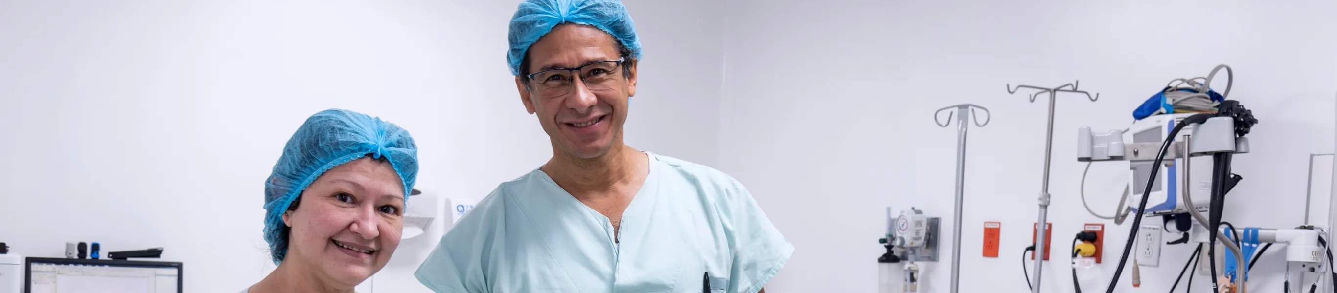 En un ambiente de sala de procedimientos se ve a dos profesionales de la salud a la izquierda y a la derecha se ven equipos médicos